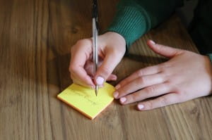 Hands writing on a post-it note