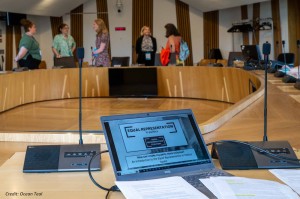 Laptop screen with workshop slides; people chatting in background
